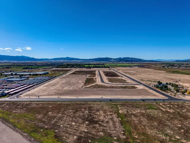 Expansive undeveloped land featuring a clear sky, distant mountain range, and a paved roadway