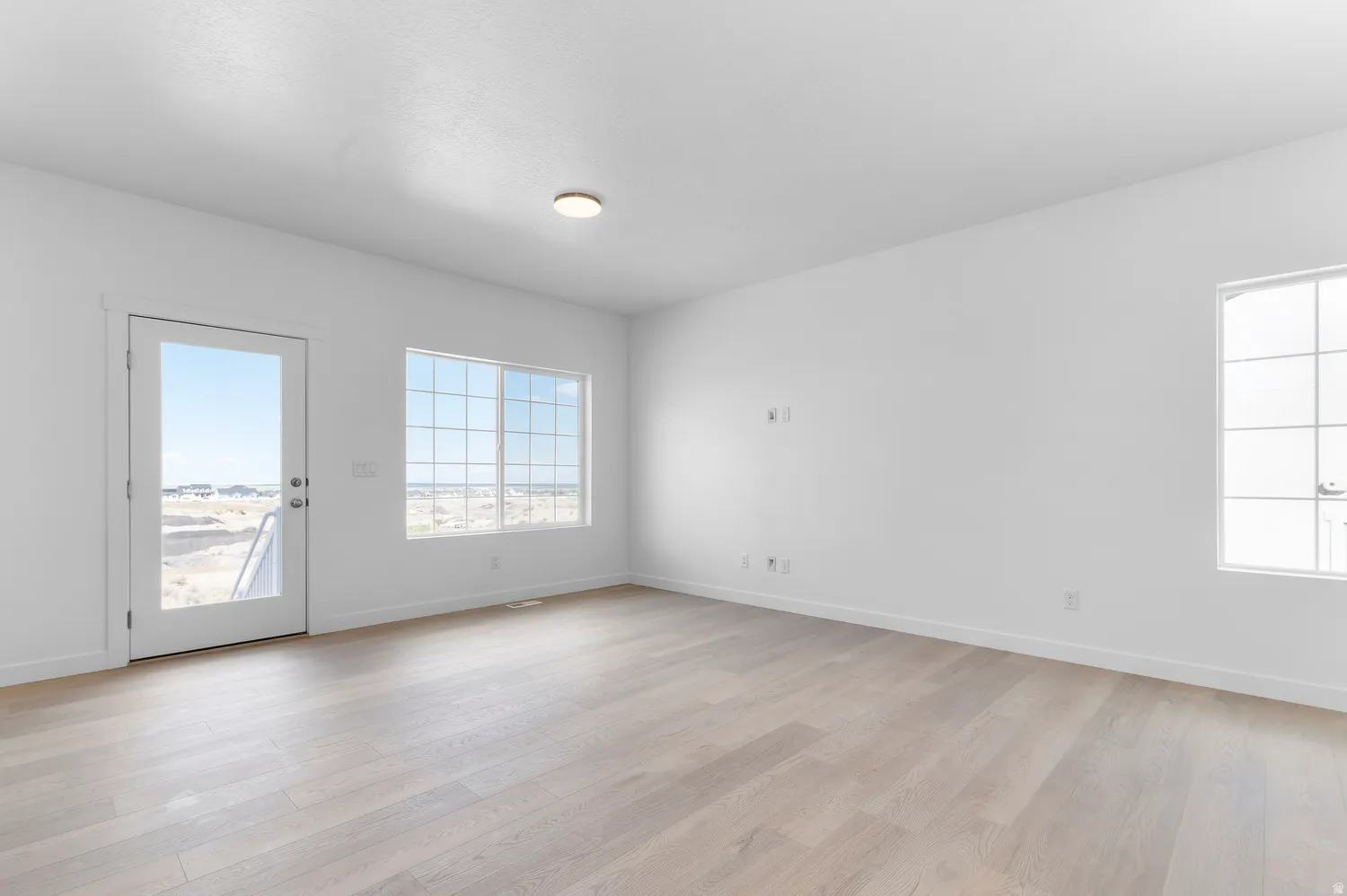 Light wood-finish flooring, recessed ceiling light, and multiple large windows with grid patterns