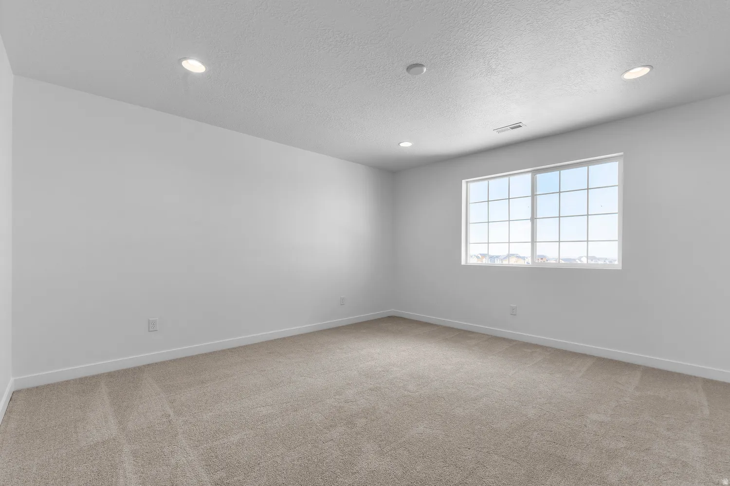Neutral tone wall paint, light-colored carpet flooring, window with grid panes, recessed ceiling lighting, and ceiling-mounted air vent