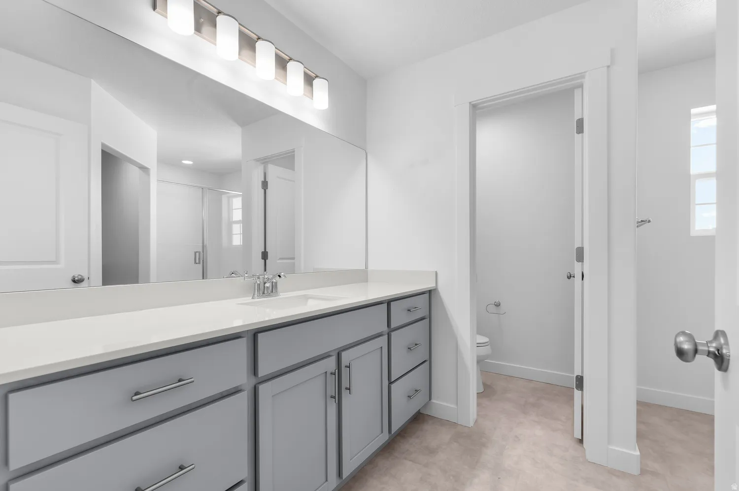 Dual vanity with gray cabinetry, white countertop, and brushed nickel hardware