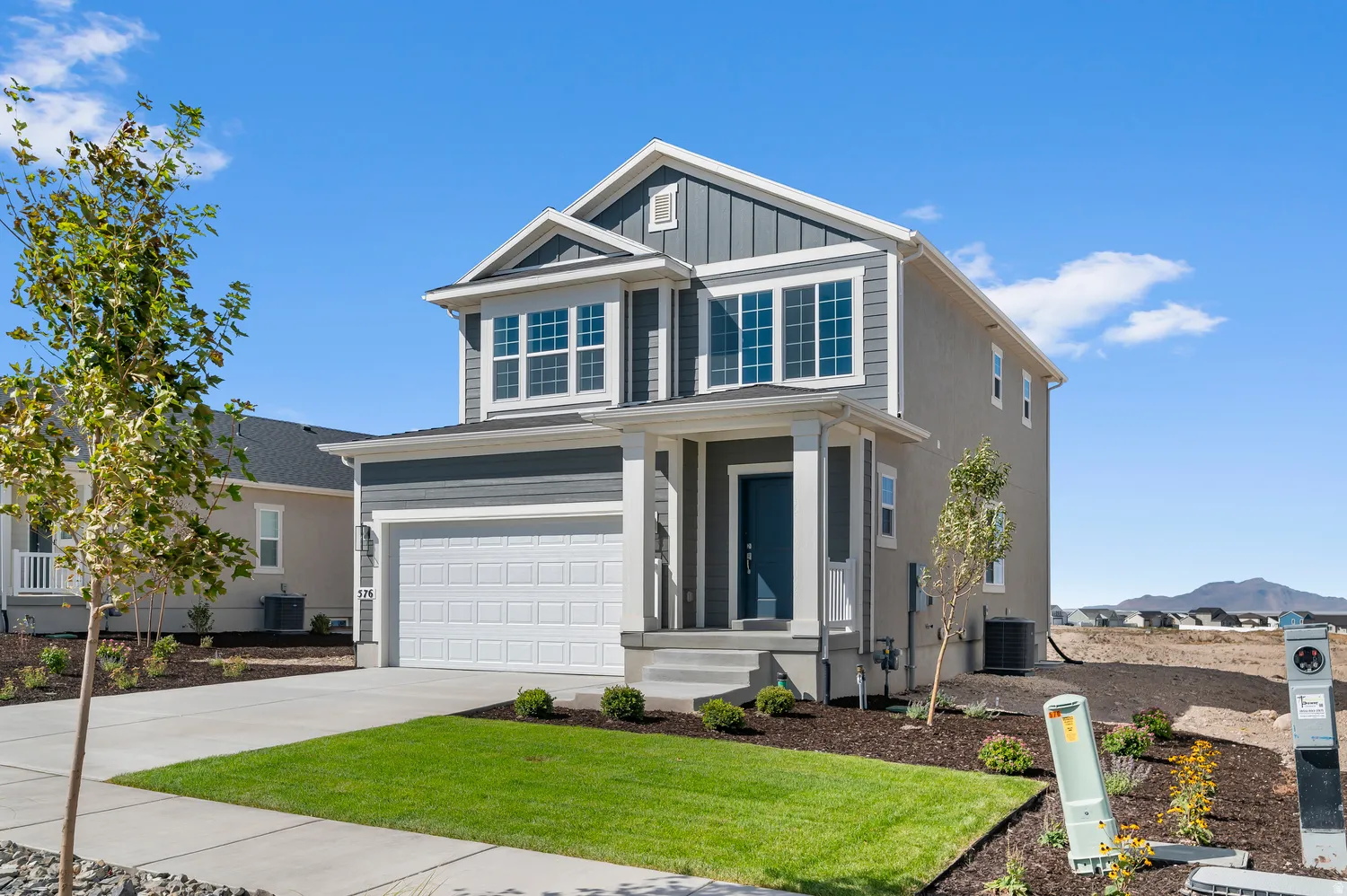 Two-story residence featuring a gray exterior with board and batten accents, a single-car garage, and a covered entry