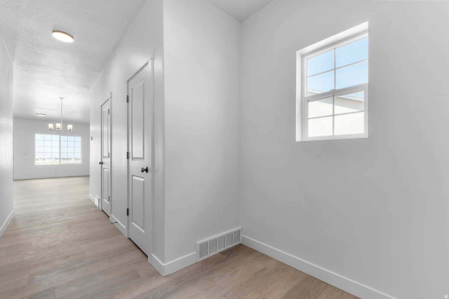 Recessed lighting, wood-finish flooring, white paneled doors with black hardware, and a window with grilles