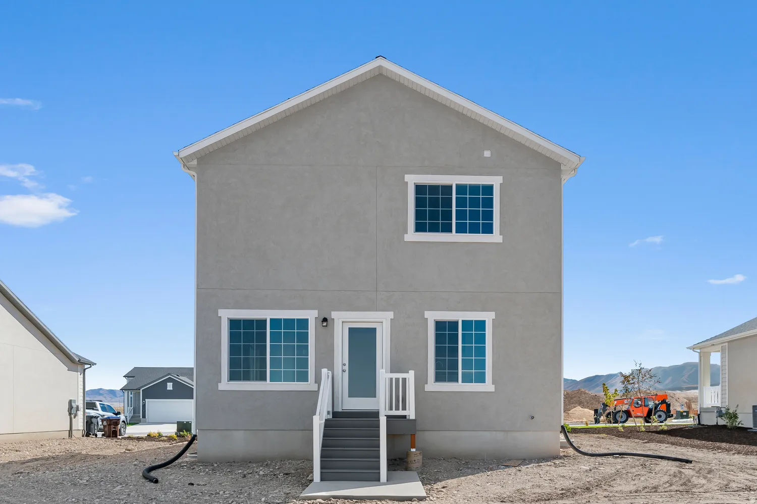 Two-story stucco exterior featuring multiple windows with white trim
