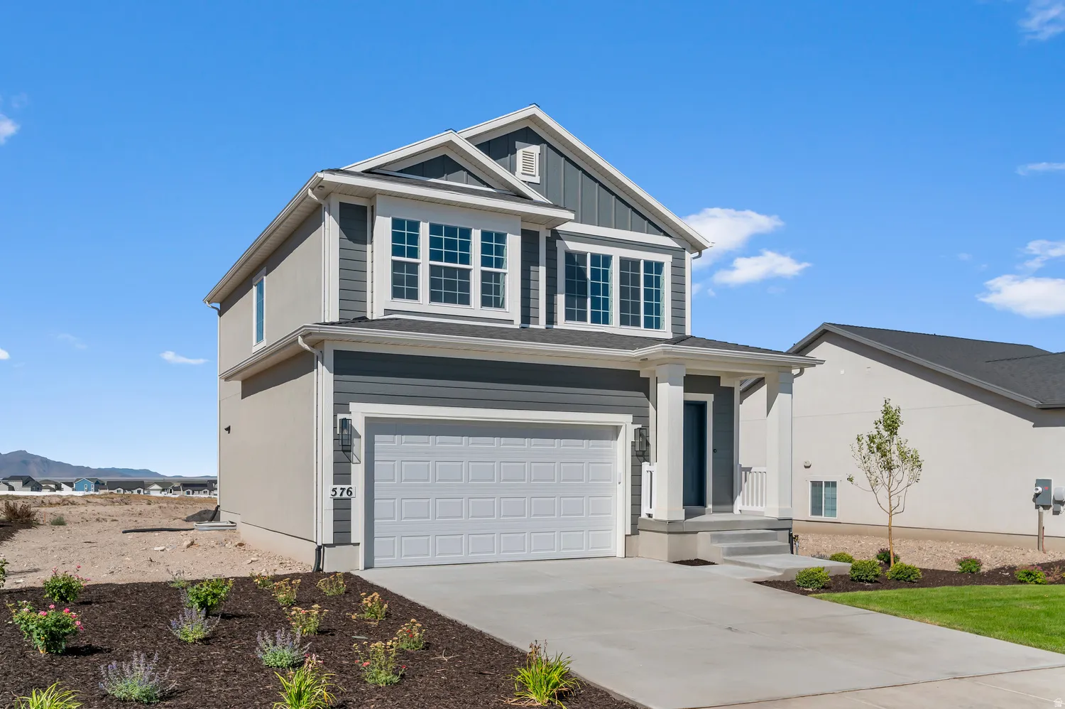 Two-story residence featuring a two-car garage, covered entry, front landscaping, and a concrete driveway