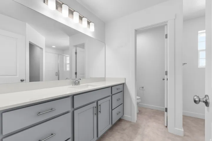 Dual vanity with gray cabinetry, white countertop, and brushed nickel hardware