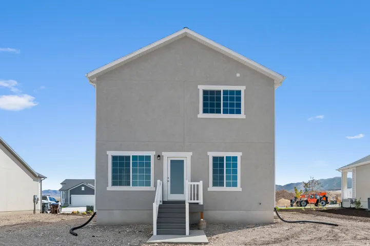 Two-story stucco exterior featuring multiple windows with white trim