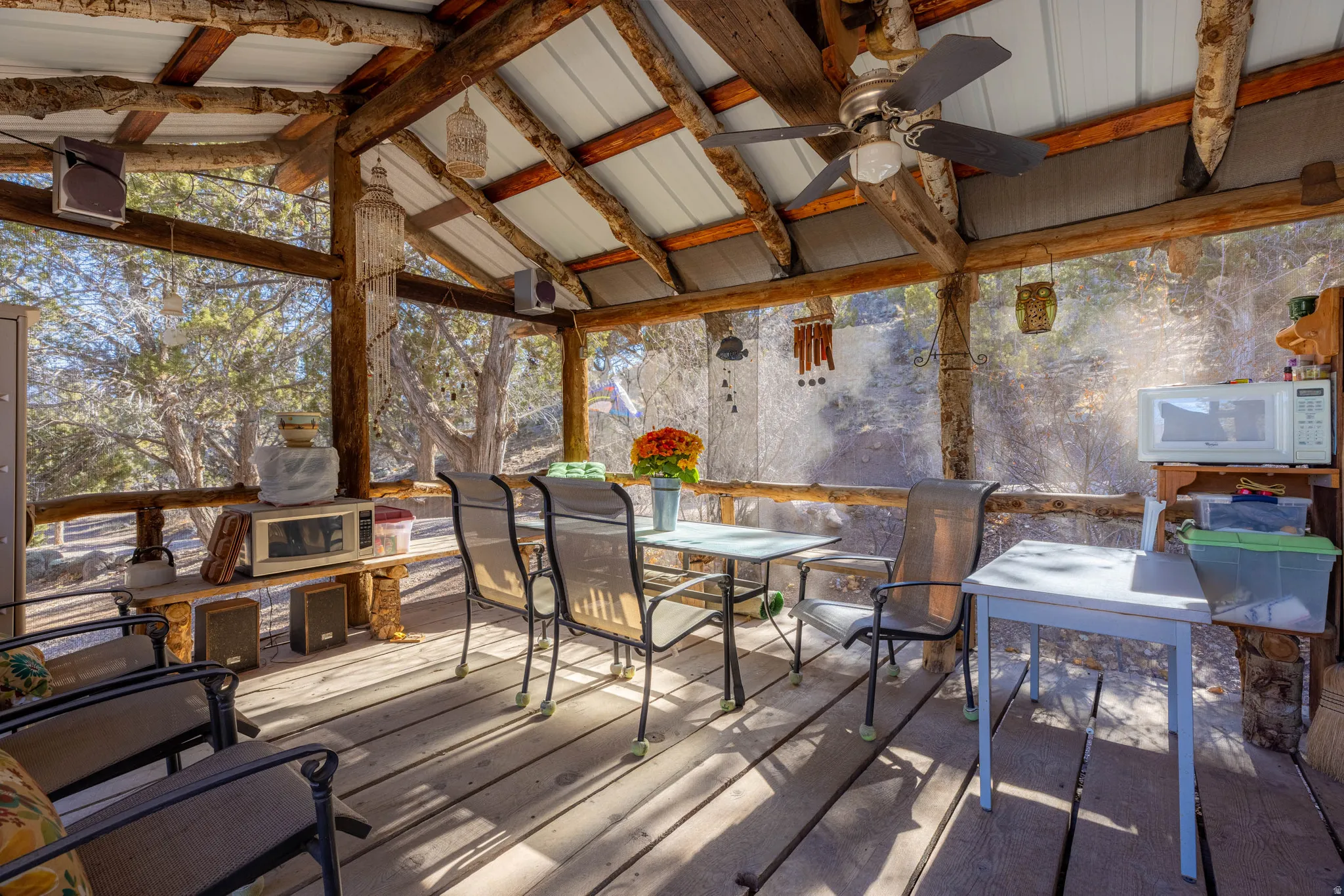 Screened porch featuring wood posts, a metal ceiling, and a ceiling fan