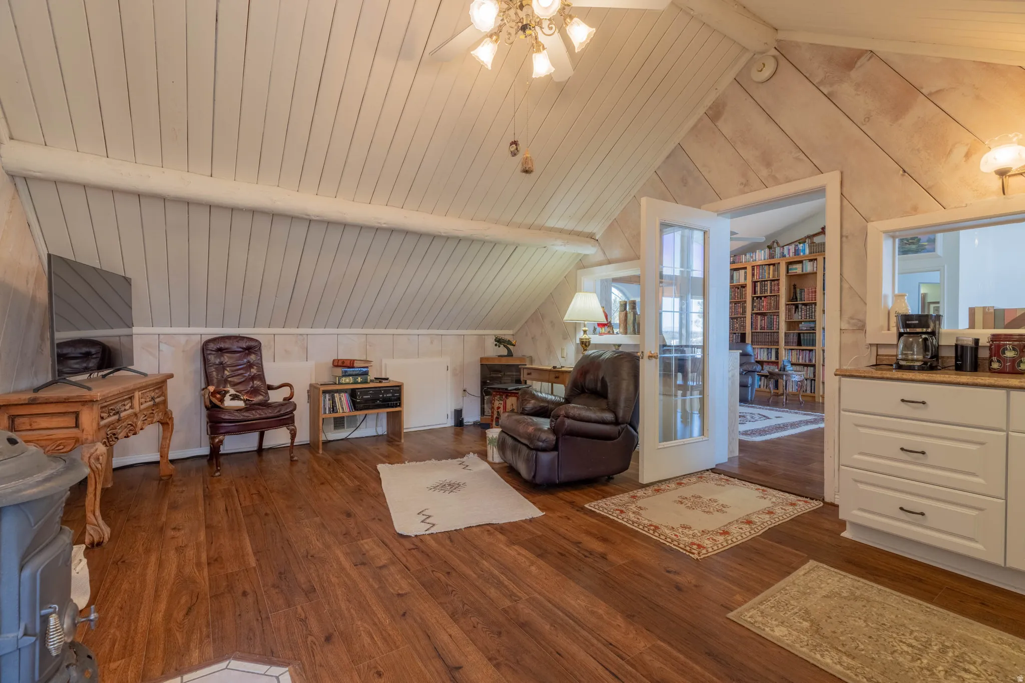 Vaulted ceiling with wood paneling, wood-finish flooring, white built-in cabinetry, and white French doors