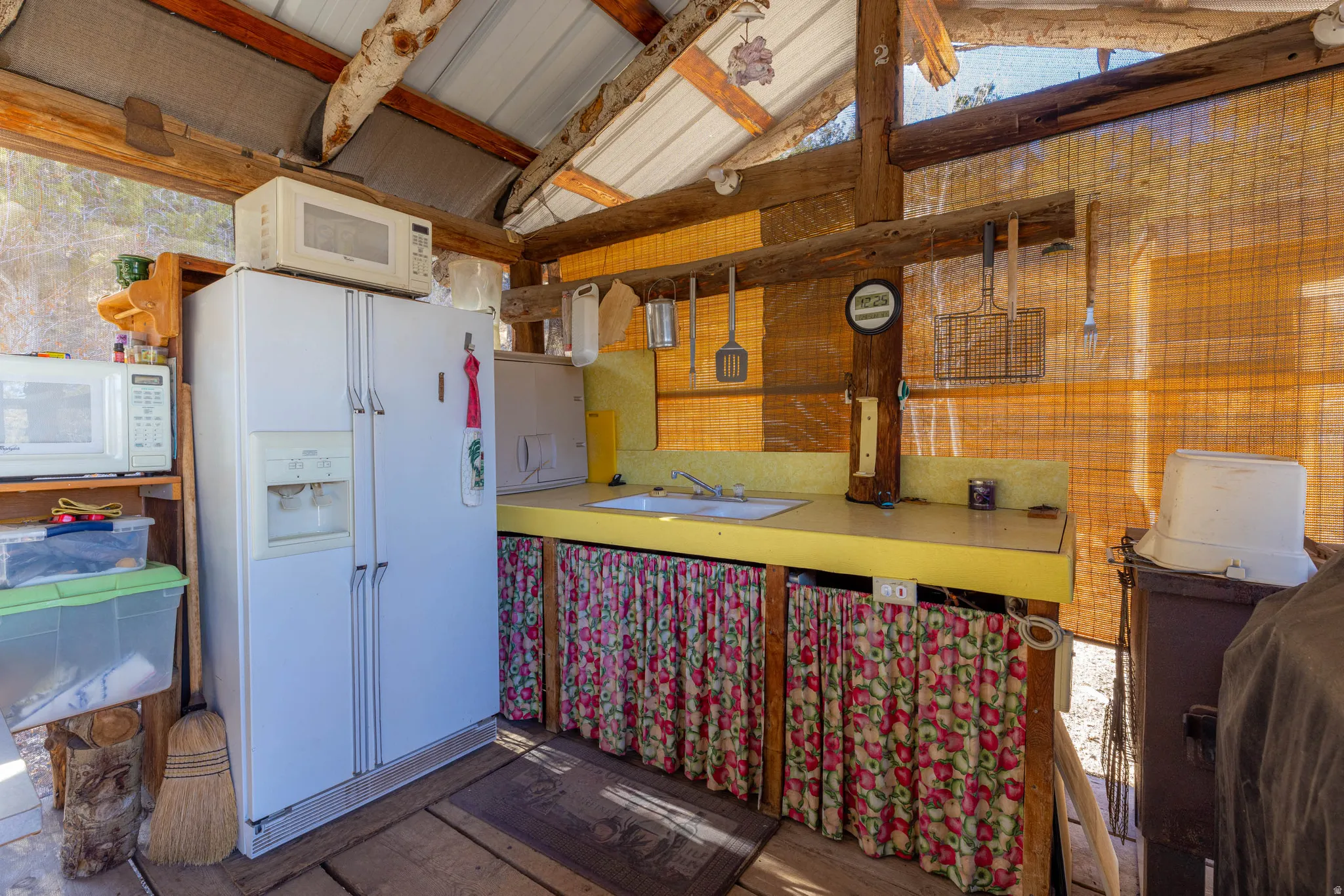 Corrugated metal roofing, exposed wood beam framing, yellow laminate countertop, built-in sink, and full-size refrigerator