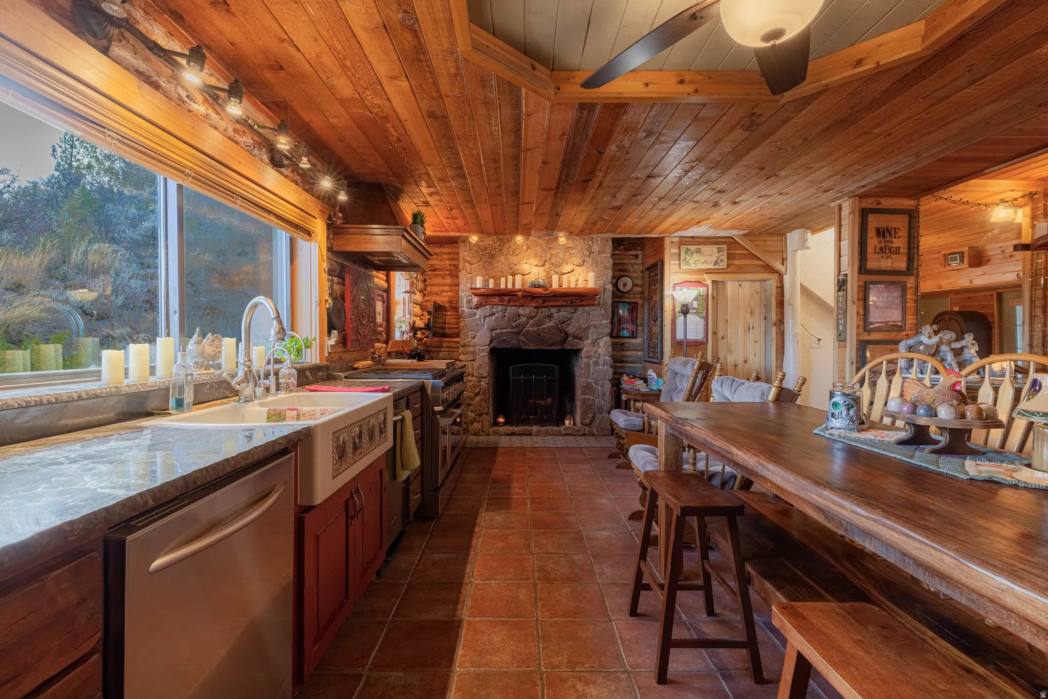 Wood-paneled ceiling, stone fireplace, tile flooring, wood-finish countertops, and farmhouse sink