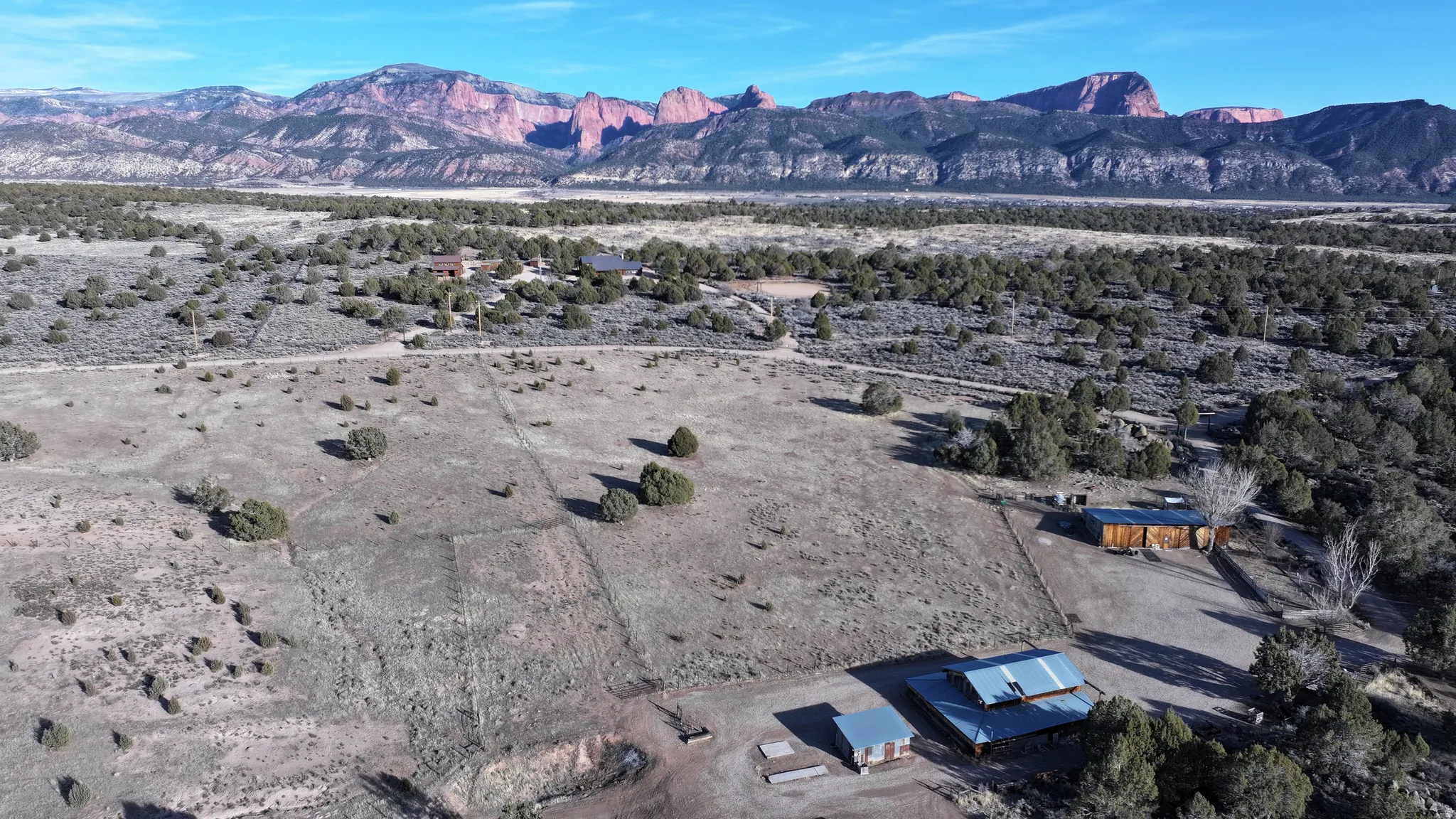 Expansive property with multiple structures, natural landscaping, and a distant mountain backdrop