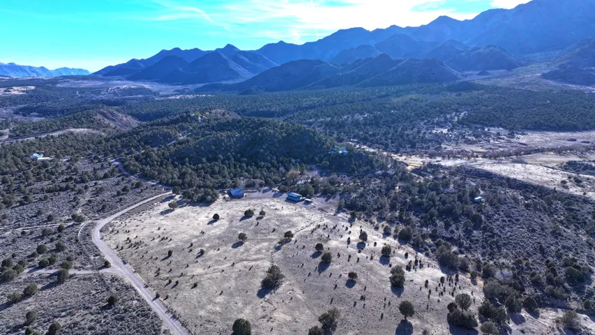 Mountainous terrain with natural landscaping, a winding unpaved road, and distant structures