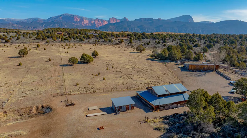 Expansive property featuring a primary structure with a metal roof, additional outbuildings, and natural landscaping with scattered trees