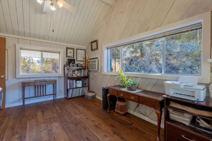 Vaulted ceiling with a ceiling fan, wood-finish flooring, built-in window, and a built-in bookshelf