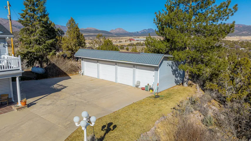 Detached multi-car garage with a metal roof and light blue siding, set against a mountainous backdrop