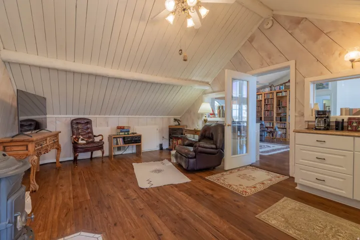Vaulted ceiling with wood paneling, wood-finish flooring, white built-in cabinetry, and white French doors