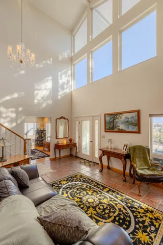 Vaulted ceiling with transom windows, crystal chandelier, tile flooring, and a staircase with wood newel posts