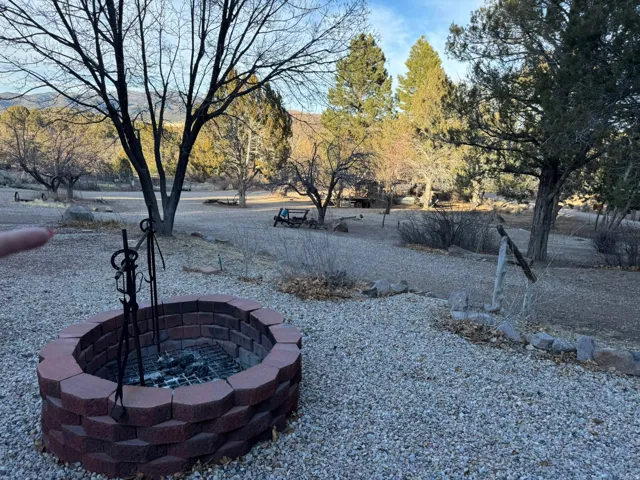 Landscaped outdoor area featuring a paver fire pit, gravel ground cover, and mature trees