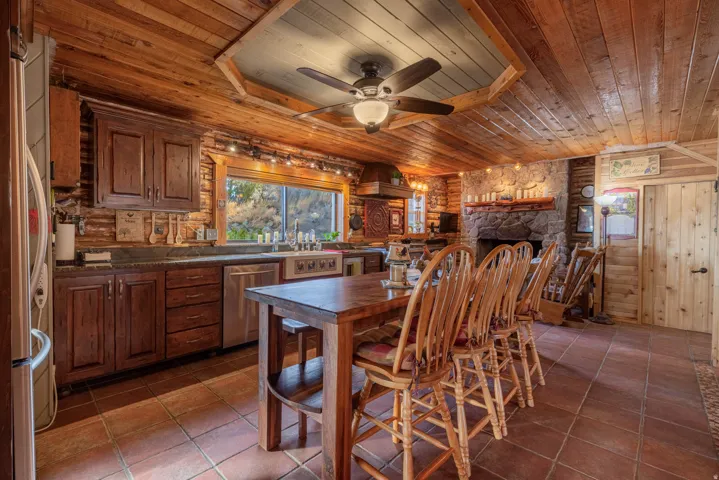 Wood-paneled ceilings, stone fireplace, wood-finish cabinetry, stainless steel appliances, and tile flooring