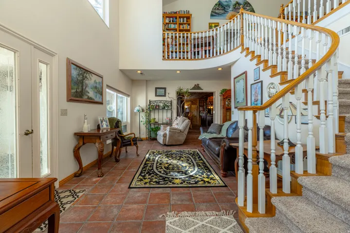 Two-story foyer featuring a curved staircase with wood handrails, a second-story balcony, and tiled flooring