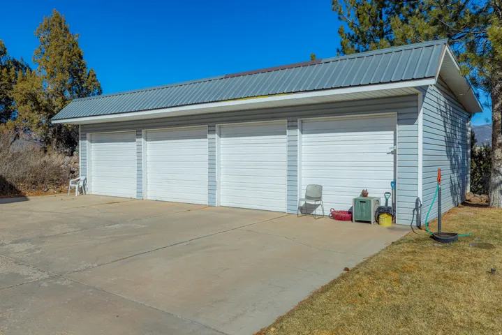 Three-car garage with light blue siding and a metal roof