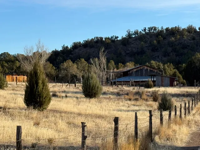 Expansive property featuring a rustic barn structure, natural landscaping, and a post-and-barbwire fence