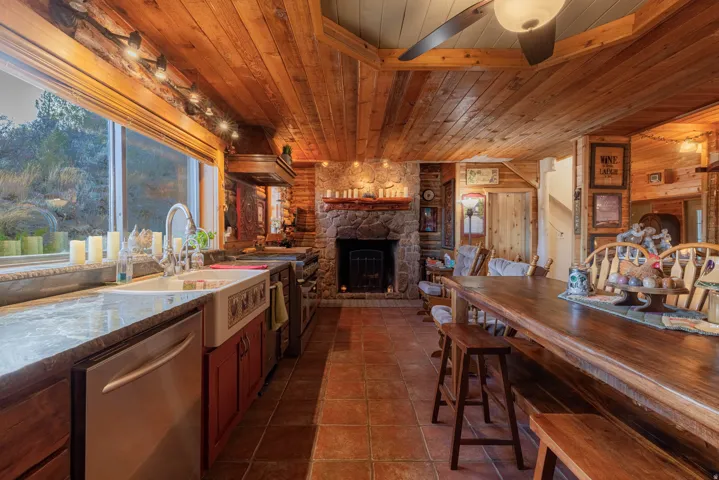 Wood-paneled ceiling, stone fireplace, tile flooring, wood-finish countertops, and farmhouse sink