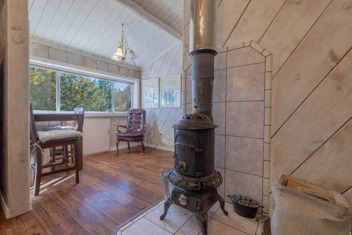 Wood-finish flooring, paneled walls, and a vaulted ceiling with exposed beams