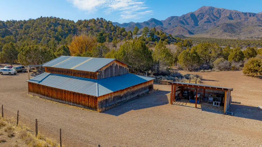 Expansive property featuring a two-story barn with metal roofing, an open-sided storage structure, and a natural, unlandscaped terrain