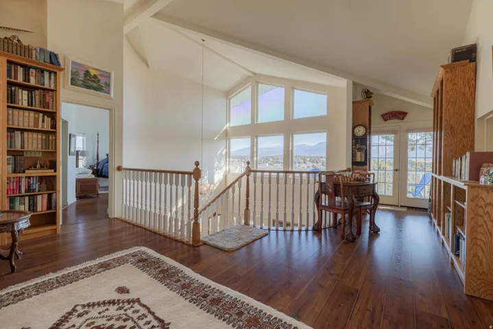 Hardwood flooring and a vaulted ceiling complement the white walls