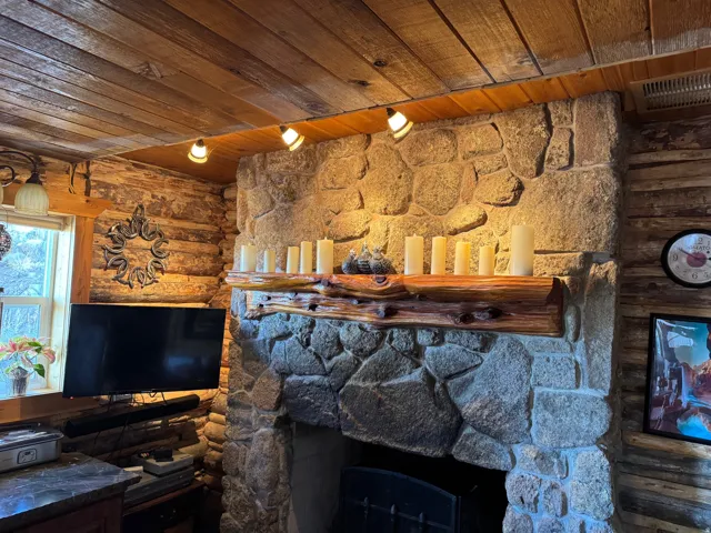 Stone-clad fireplace with a natural wood mantel