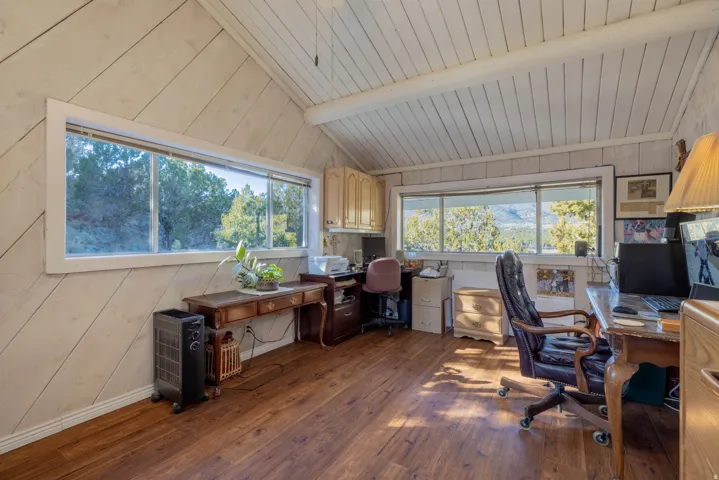 Wood-finish flooring, white paneled walls, and a vaulted paneled ceiling