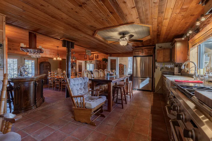 Expansive open-concept living area showcasing rich wood-finish ceilings, wood-finish flooring, and abundant natural light