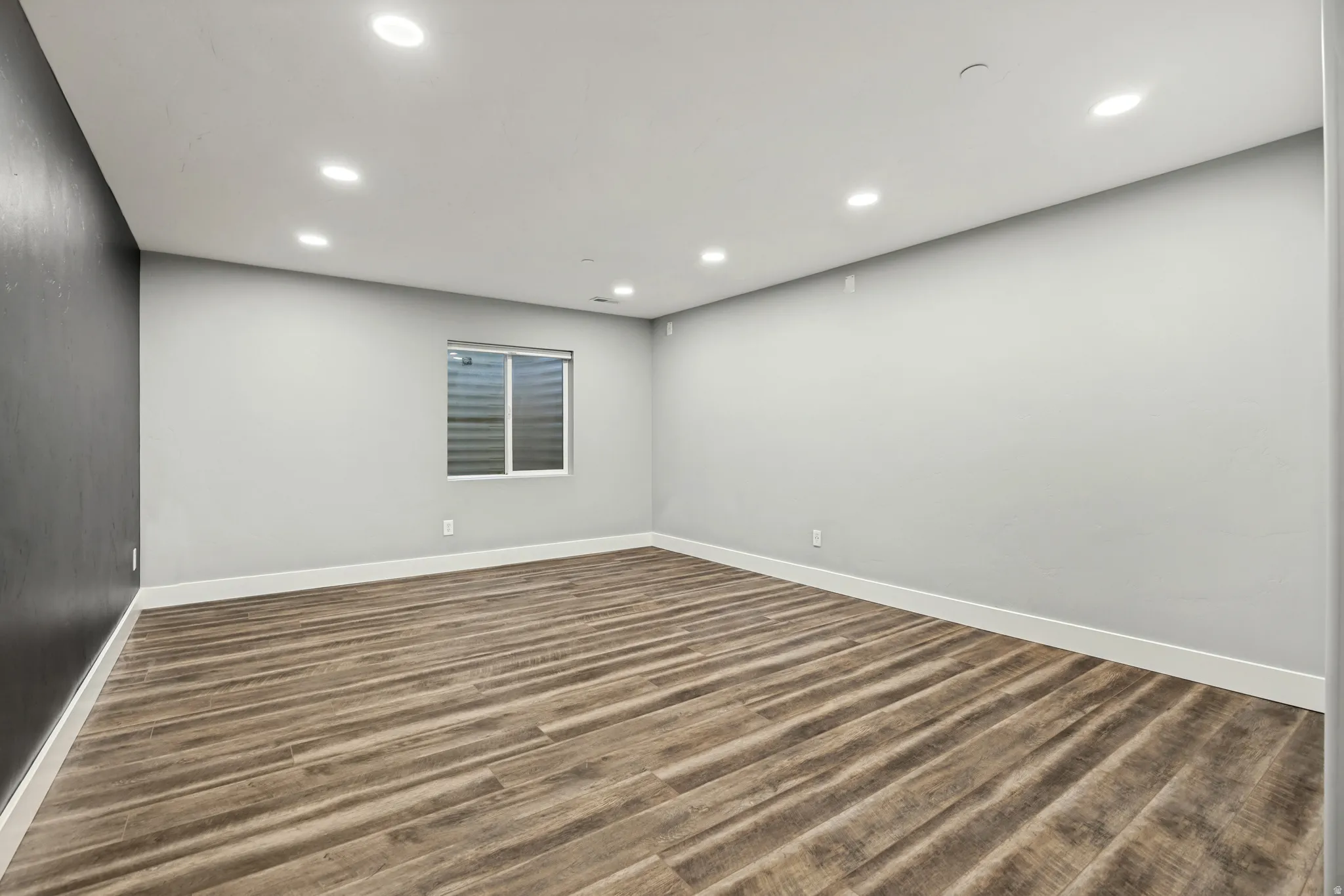 Recessed lighting illuminates wood-finish flooring