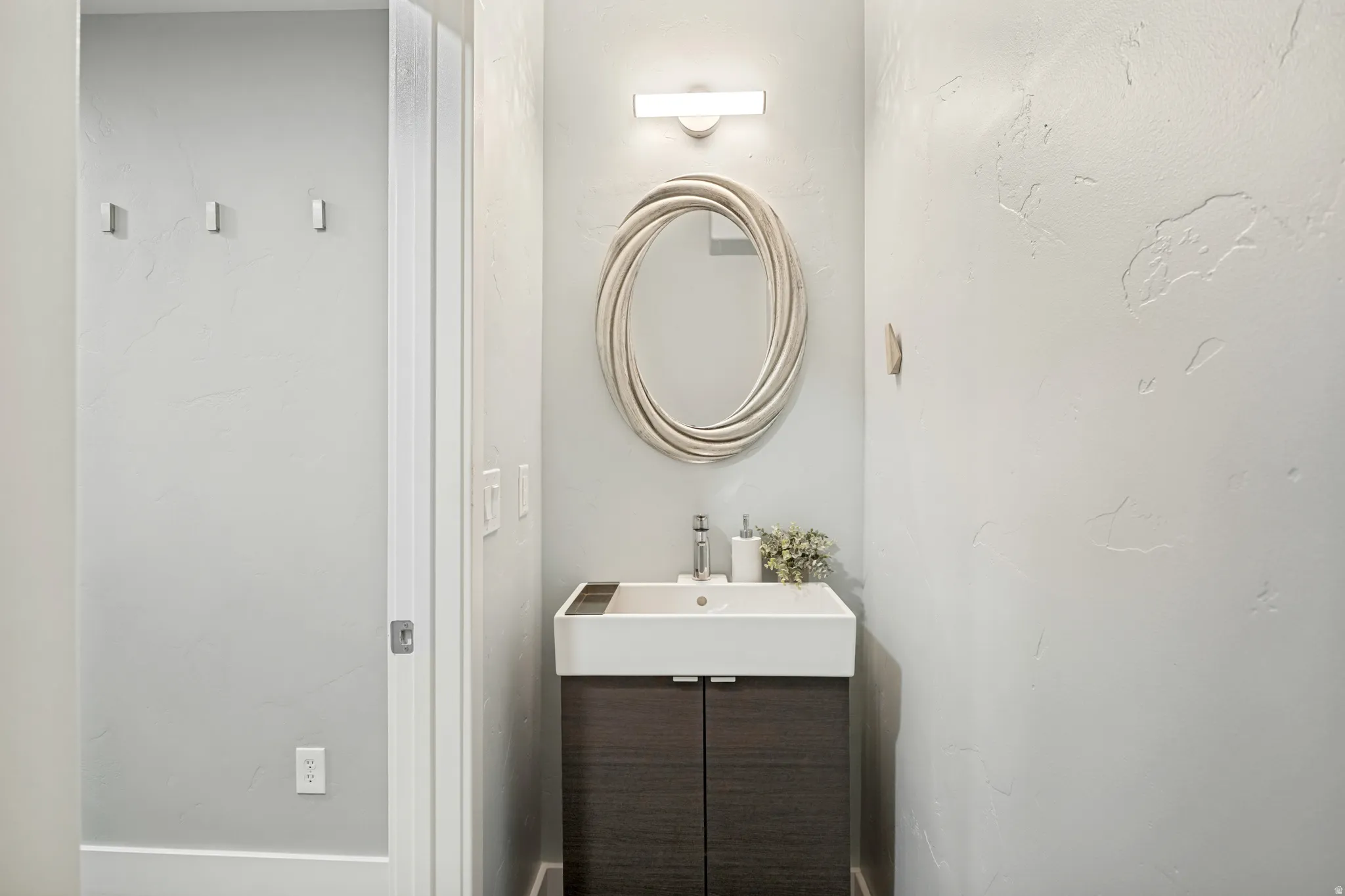 Built-in vanity with integrated sink, wood-finish cabinetry, and wall-mounted mirror