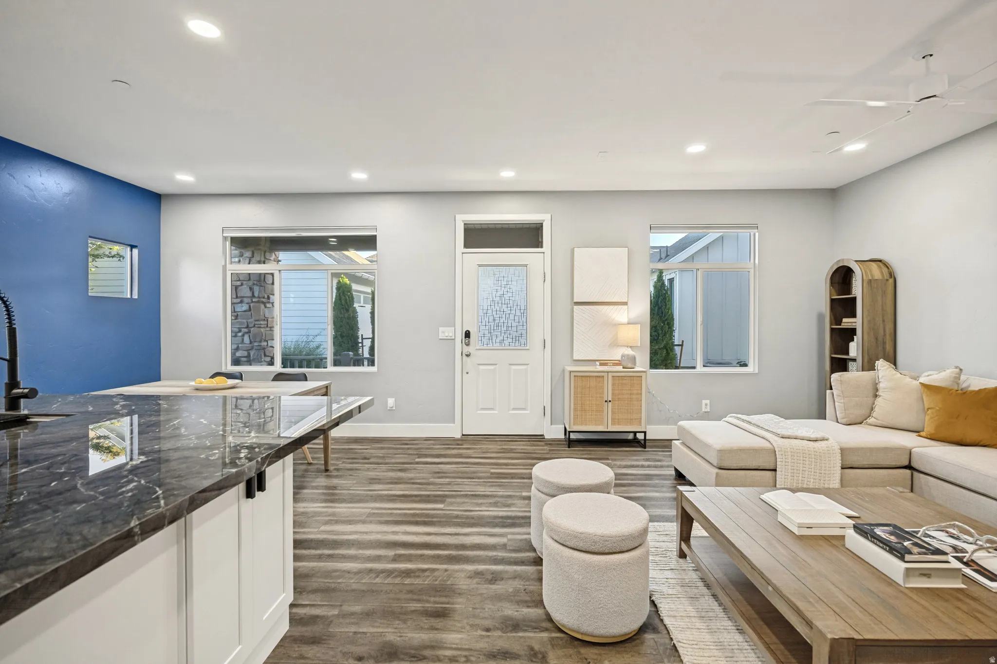 Open-concept living space featuring wood-finish flooring, recessed lighting, and a kitchen island with a dark polished countertop
