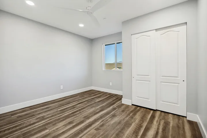 Recessed lighting, ceiling fan, wood-finish flooring, sliding panel closet, and window