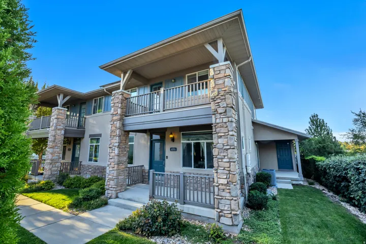 Multi-level exterior with stone veneer columns, multiple balconies, and a covered entry