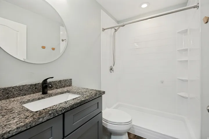 Modern bathroom featuring a single vanity with a granite countertop, undermount sink, and a matte black faucet