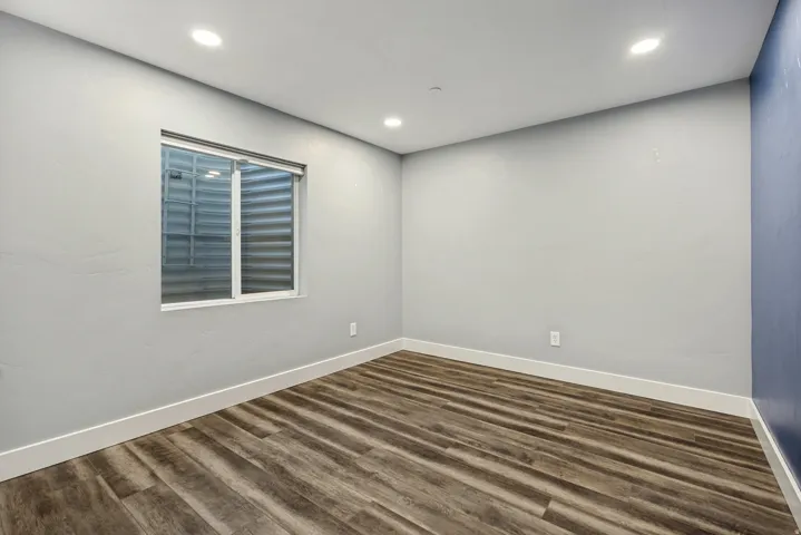 Recessed ceiling lighting, wood-finish flooring, white trim, and a window with a white frame