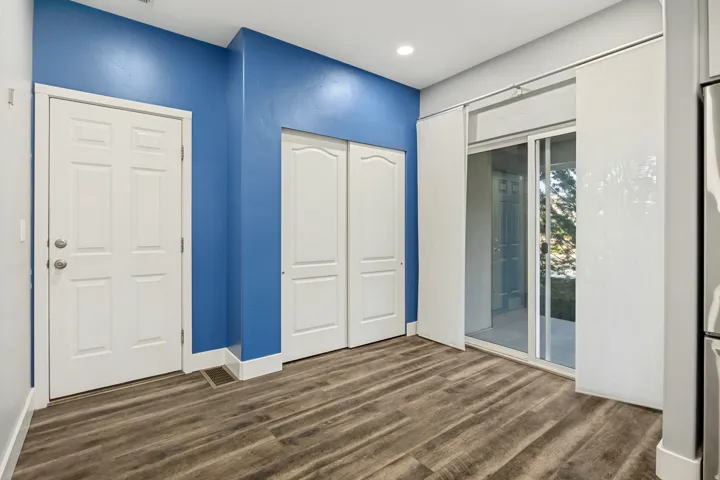 Wood-finish flooring, sliding glass door with privacy panels, white paneled doors, and recessed ceiling lighting