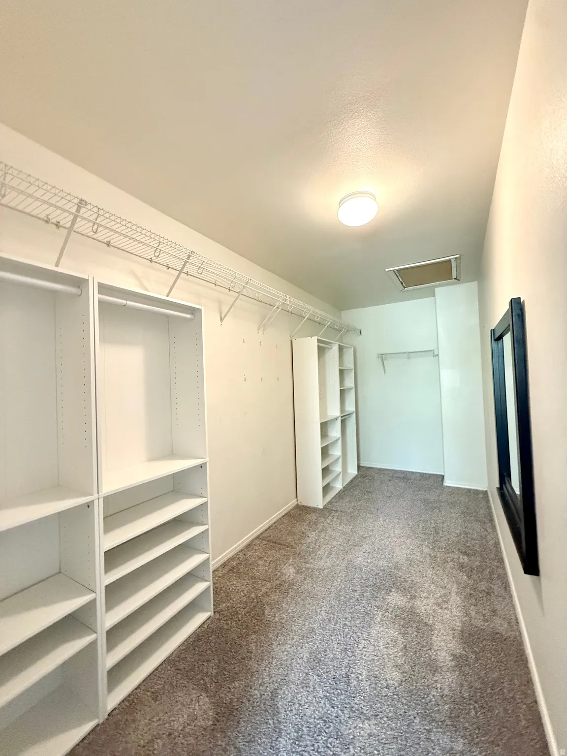 White built-in shelving, wire shelving, and neutral carpeting