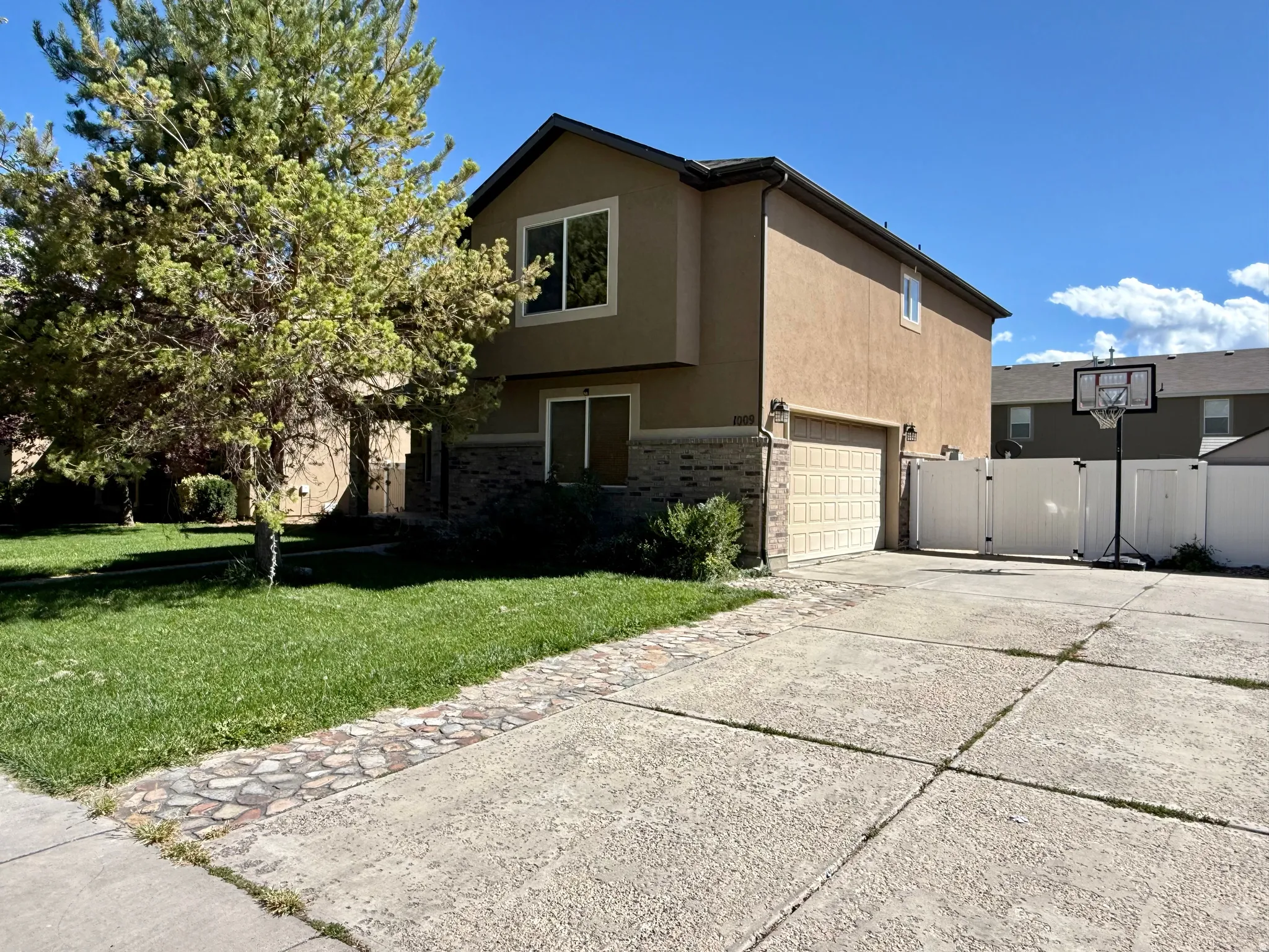 Two-story stucco exterior with stone veneer accents, an attached garage, a privacy fence, and a concrete driveway