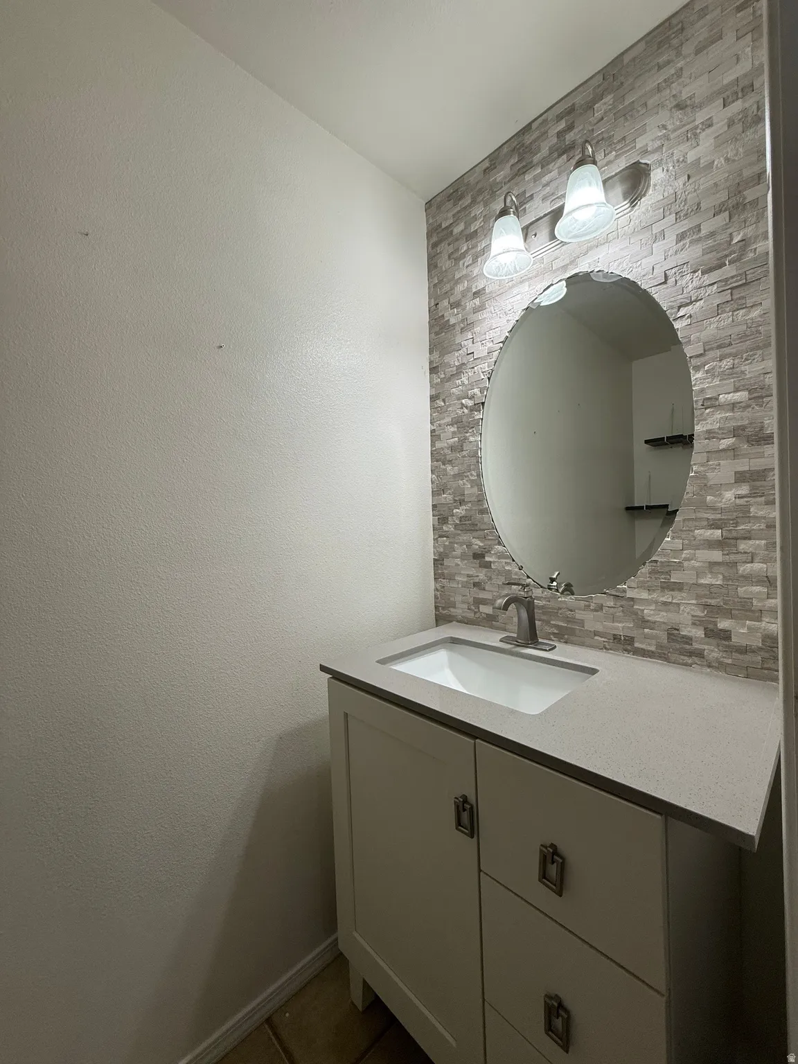 Vanity with a built-in sink, gray countertop, and white cabinetry
