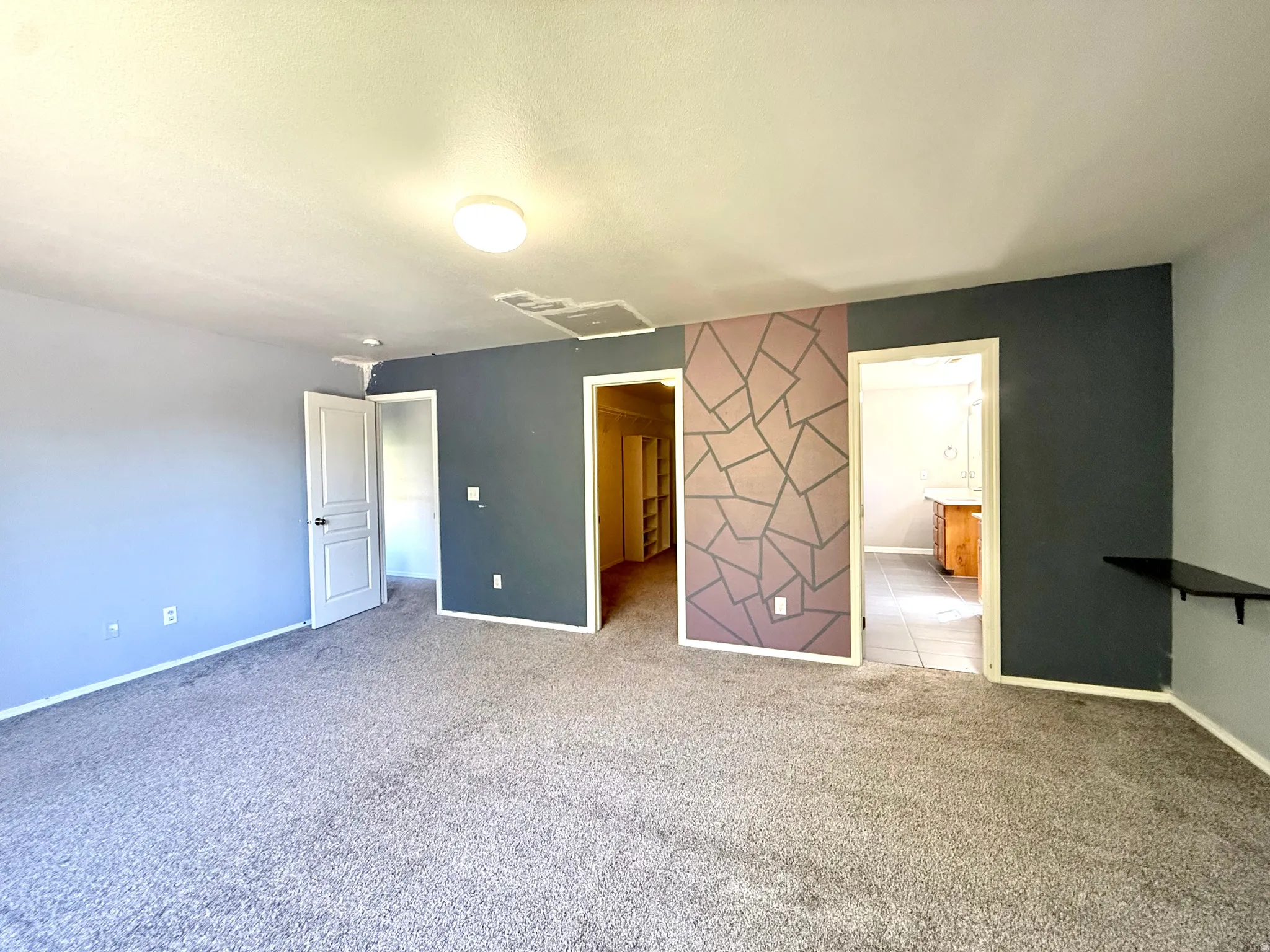 Recessed lighting, patterned accent wall, and carpet flooring