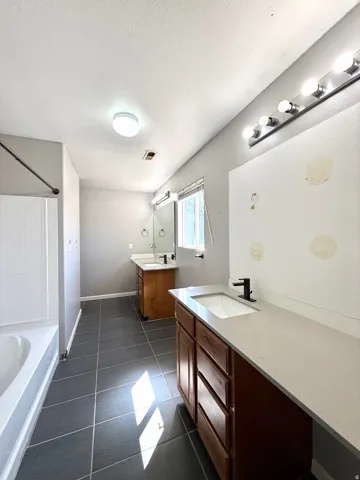 Dual vanity with white undermount sinks, stone-finish countertops, and matte black fixtures