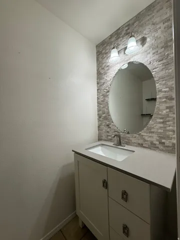 Vanity with a built-in sink, gray countertop, and white cabinetry