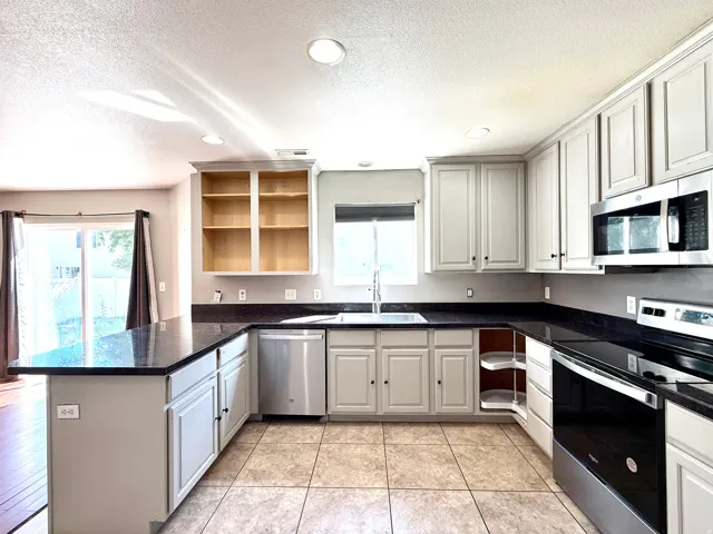 Kitchen with dark countertops, light cabinetry, tile flooring, and stainless steel appliances