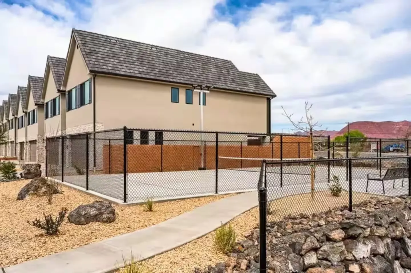 Exterior featuring neutral stucco siding, stone veneer accents, and a shingle roof