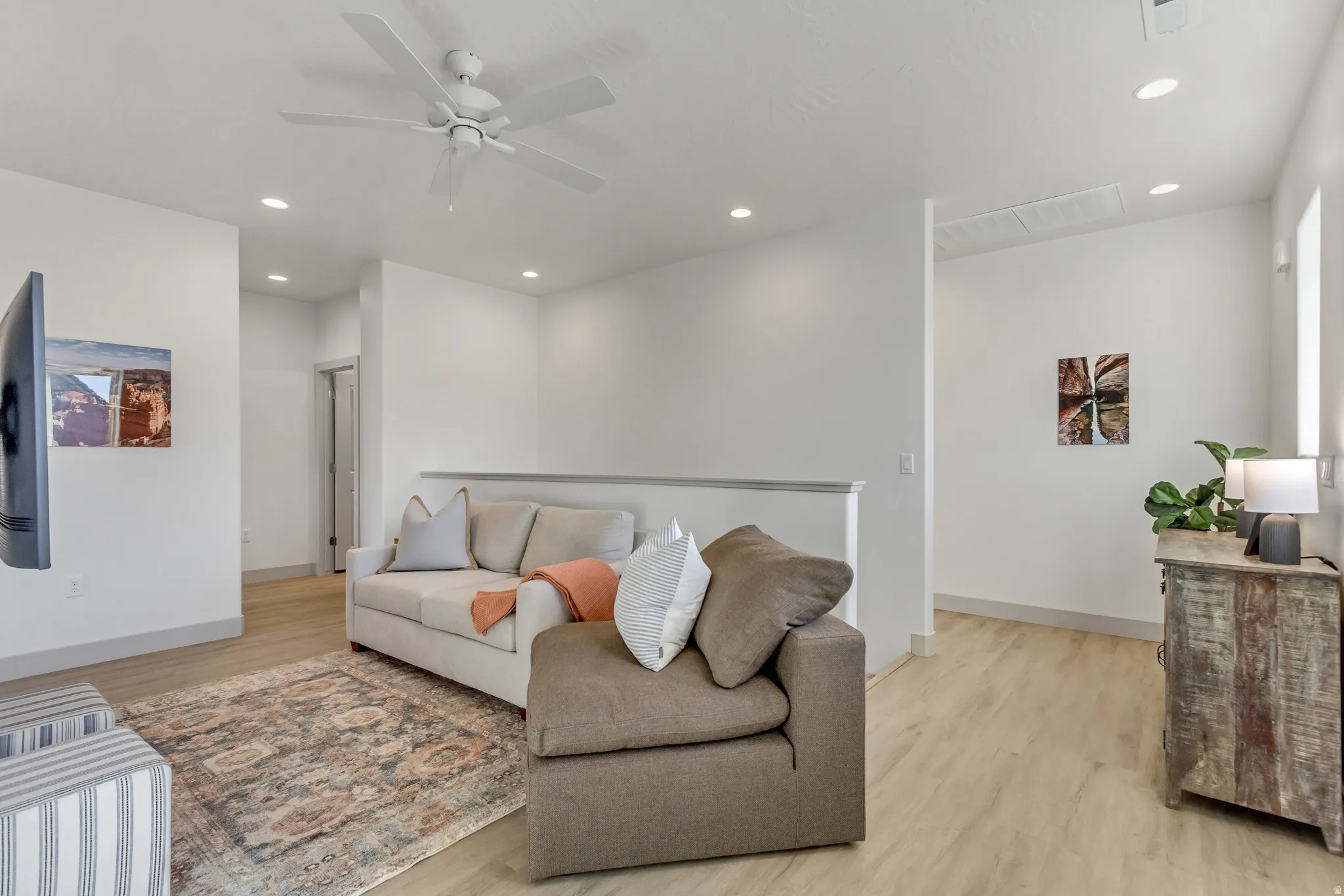 Recessed ceiling lighting, wood-finish flooring, ceiling fan, and white painted walls
